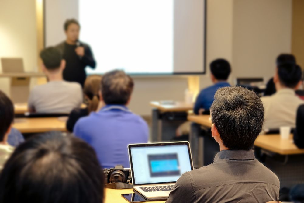 A man presenting to an audience in a conference room.